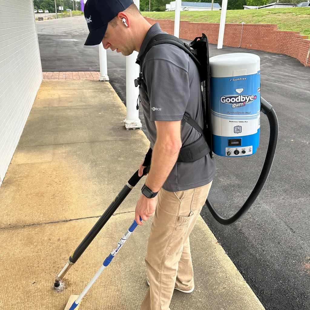 A person uses a backpack device to remove gum from pavement.