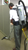Operator using an IPC Eagle Backpack Vacuum cleaning floors with a floor wand